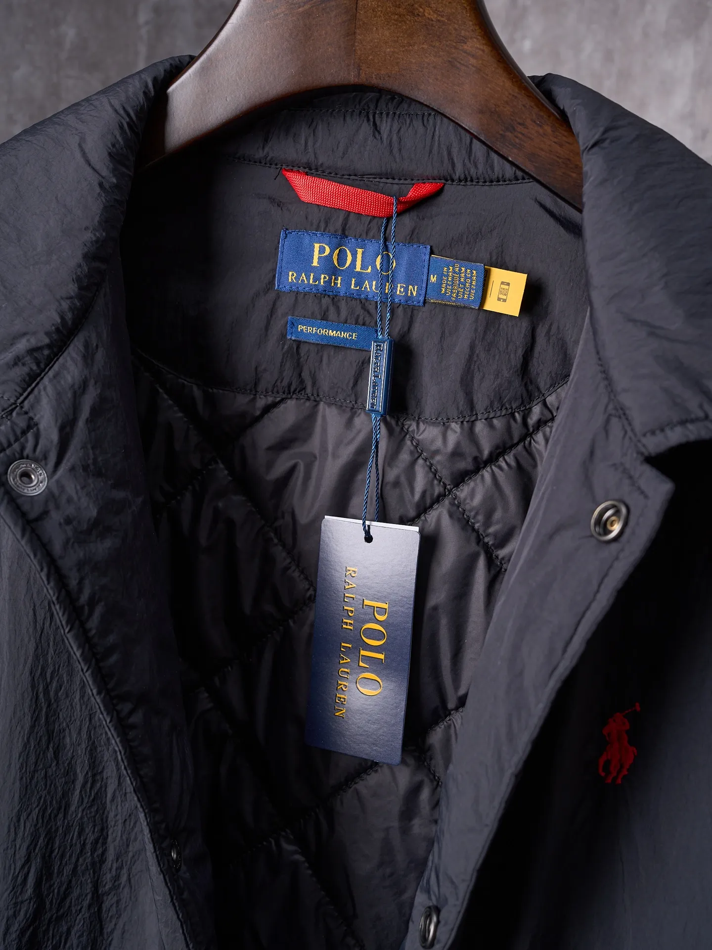 P640 Actual auction] Ralph Lauren/Ralph Lauren Pony Red Label lightweight cotton lapel coach jacket [Ready stock] S M L XL Material: high-density nylon taffeta Features: Density is about 210T-300T, smooth and slightly matte surface, excellent windproof and waterproof performance (with DWR water-repellent treatment), strong wrinkle resistance and easy care, in line with the positioning of American casual "durable and practical".  Color: Classic dark black, using vat dyeing process (dye penetrates into the fiber), the color fastness reaches ISO level 4 or above to avoid fading or color transfer after washing.  2. Lining fabric Material: Lightweight cotton-polyester blended lining (65% Polyester + 35% Cotton) Function: Reduce friction between the fabric and inner clothing, improve wearing smoothness; blended material has both breathability and durability to avoid the stuffy feeling of pure nylon lining.  Version and cutting process Version: Classic Coach Jacket, loose version, slightly dropped shoulder line (shoulder width is 1-2cm wider than the standard version), length to the hips, and slightly tapered straight sleeves, taking into account both freedom of movement and casual style. Embroidery technology: Polo horse logo on the left chest: flat satin stitch embroidery (satin embroidery), embroidery thread: 100% polyester high color fastness embroidery thread (the color number is consistent with the brand’s standard red color card), stitch density 12-15 stitches/cm, the outline of the horse logo is clear, and the details of the rider and horse are burr-free.  Embroidery positioning: precise positioning through the template (12cm from the neckline and 8cm from the placket) to ensure left and right symmetry and centering.  Topstitching technology: The seams of the body are made of double-needle flat seams (needle pitch 3cm/10 needles), the stitches are smooth and straight, the stitching color is dark black (the same color as the fabric), and the stitch width is 0.5cm, which enhances firmness while forming simple decorative lines.  1. Main body splicing, splicing of the front placket and body: The placket is made of double-layer folding + flat seam splicing, with a thickness of about 0.3cm to ensure that the buttons are not easily deformed when fixed; the edges of the placket are cut with a hot knife to avoid burrs.  Sleeve panels are spliced ​​to the body: the armholes are spliced ​​with round-head keyhole machine seams + flat seams. After splicing, the armholes have a natural curvature and no sense of tightness during movement; the height of the sleeves is about 8-10cm, which is in line with the loose characteristics of casual jackets.  Main button: black urea resin button, matte surface treatment, buttonholes are hand-made keyholes (6 strands of cotton thread, keyhole density 8 stitches/mm), the edges of the eyelets are smooth and without burrs.  Collar buttons: The first button on the collar is a hidden button (diameter 12mm), which prevents the collar from opening and improves the neatness of wearing.
